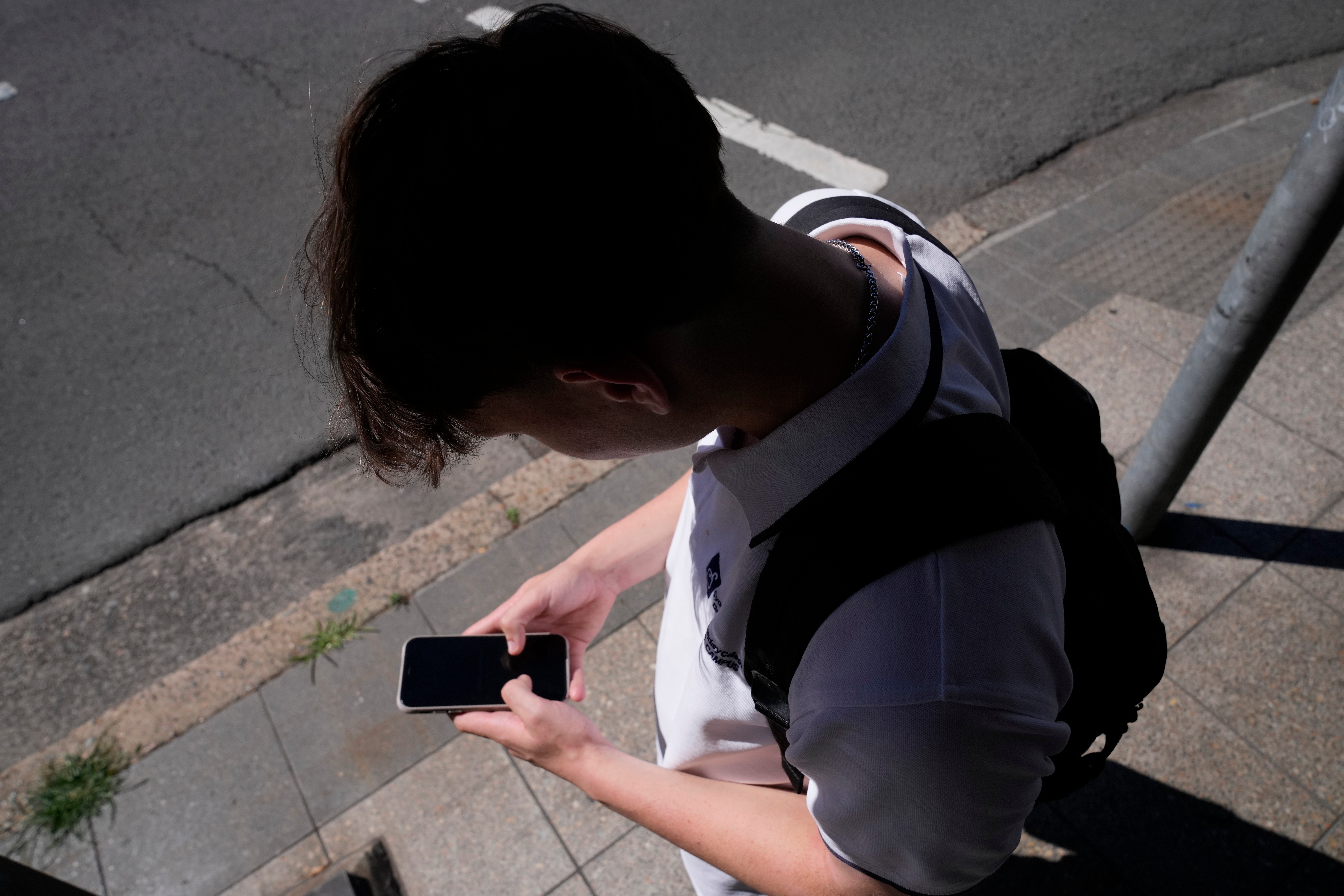 FILE - A teenage boy uses his phone in Sydney, Nov. 8, 2024.